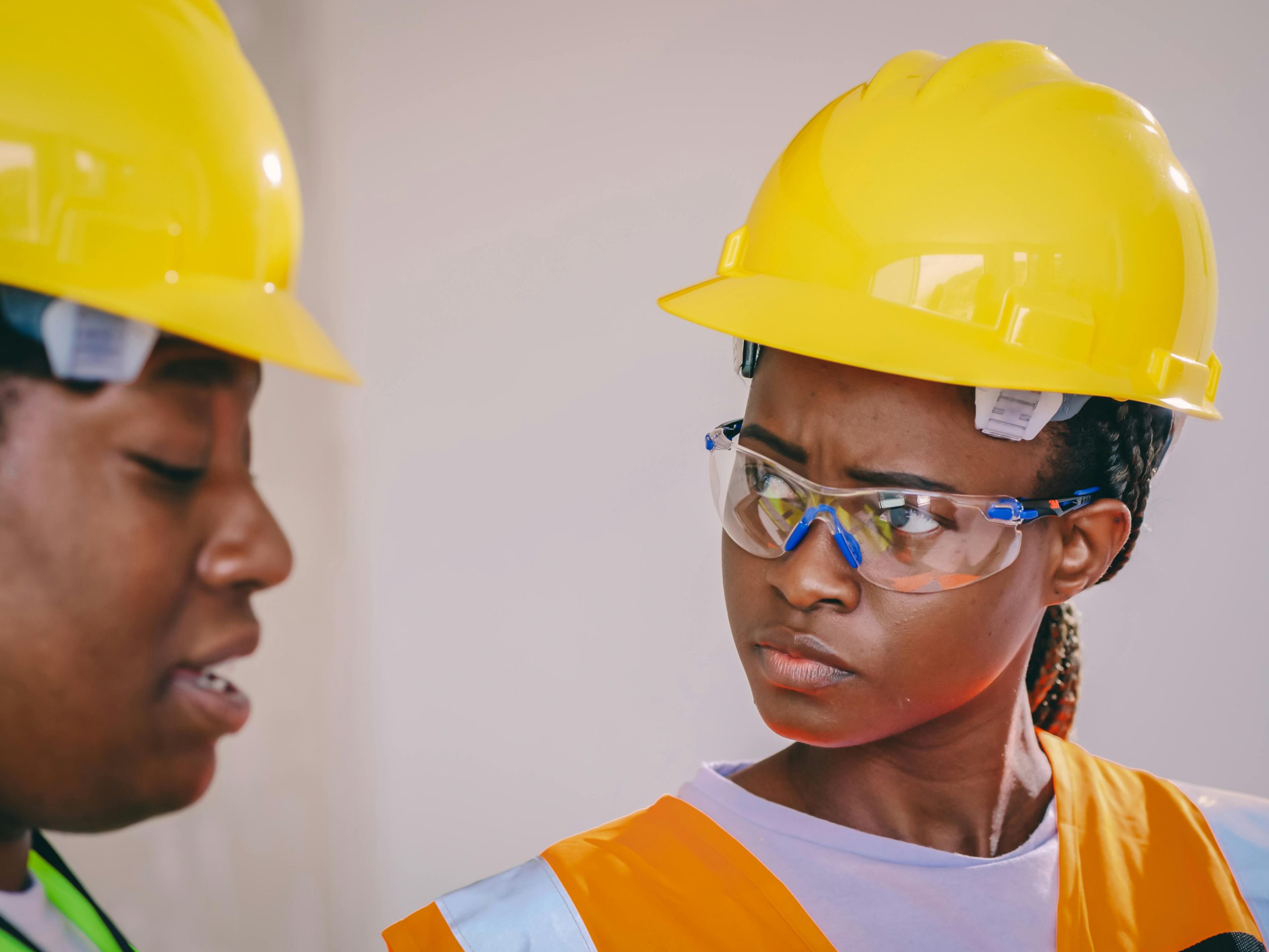 Close-up of African American construction workers wearing safety gear, including helmets and vests.